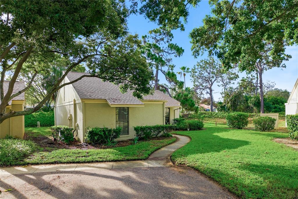 A light green house with a shingled roof sits beside a curved concrete walkway — 18 WINDRUSH BAY DRIVE, TARPON SPRINGS, FL