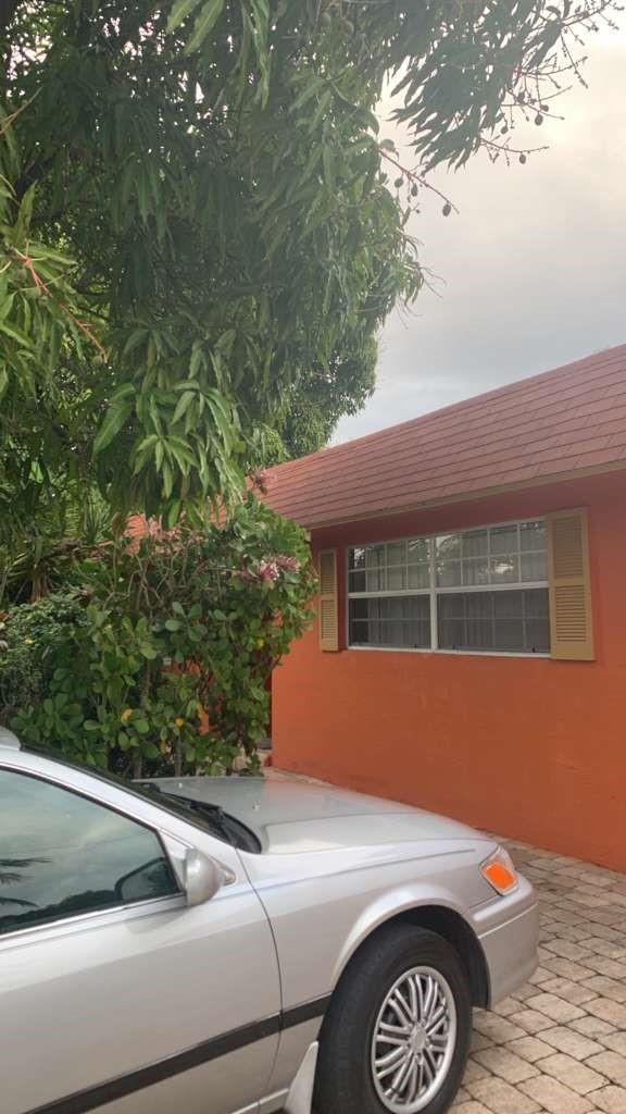 A silver sedan is parked on a paved driveway next to an orange house exterior — 2070 NE 2nd Avenue, Pompano Beach FL 33060, POMPANO BEACH, FL