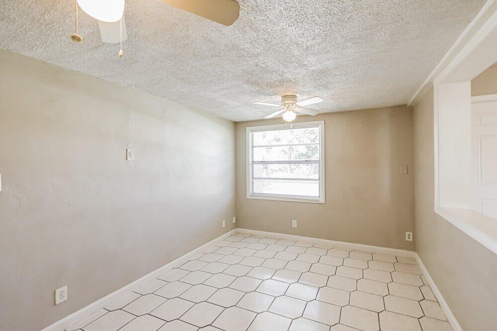 An empty room features beige walls, a white ceiling fan, and white hexagonal floor tiles — POMPANO BEACH, FL