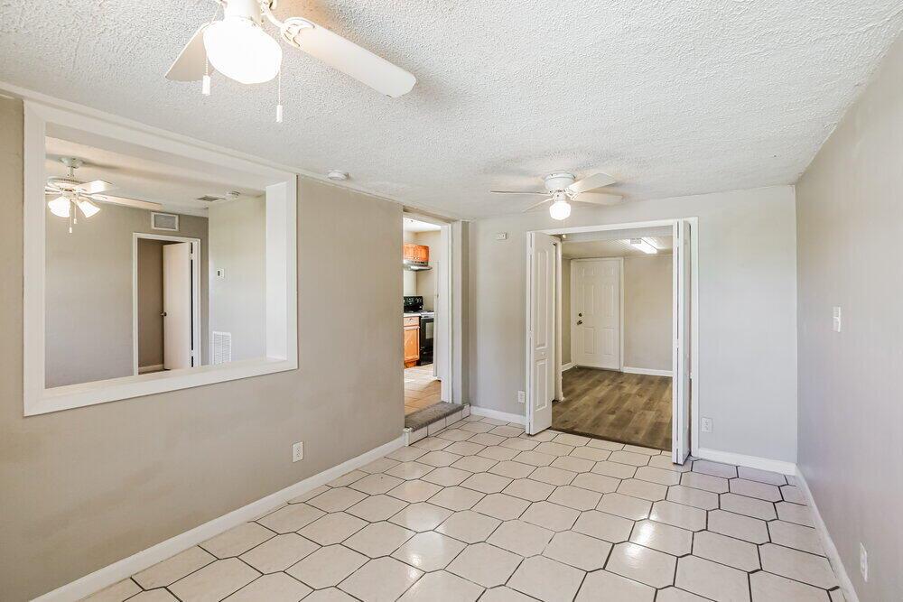 A room with light-colored tile flooring, a ceiling fan, and an opening to a kitchen — POMPANO BEACH, FL
