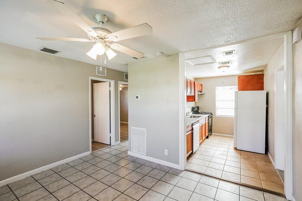 A dining area with a ceiling fan opens into a kitchen with tile flooring — POMPANO BEACH, FL