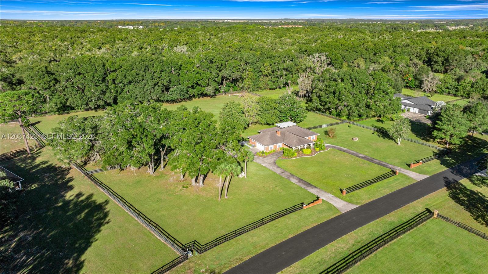 An aerial view shows a house with a large yard, fenced pastures, and surrounding trees — OCALA, FL
