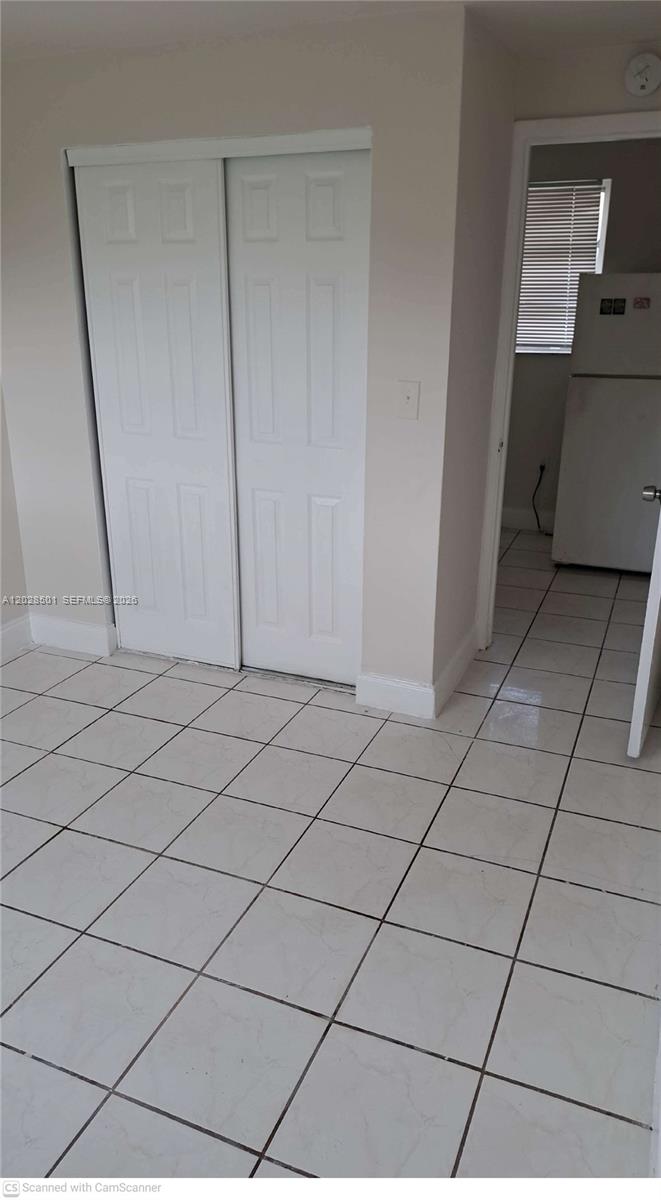 A room with white tile flooring and a white sliding-door closet leads to a kitchen — 1362 SW 2nd St # 7, Miami FL 33135, MIAMI, FL