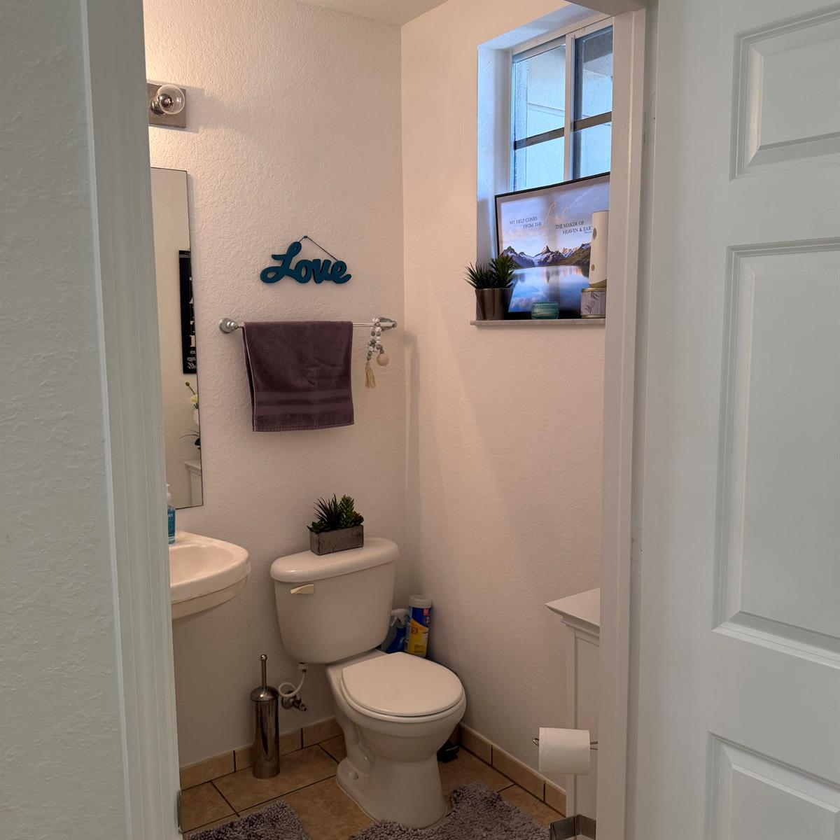 A small bathroom features a pedestal sink, a toilet, a towel rack, and a window — 976 Abaco Lane, West Palm Beach FL 33404, WEST PALM BEACH, FL