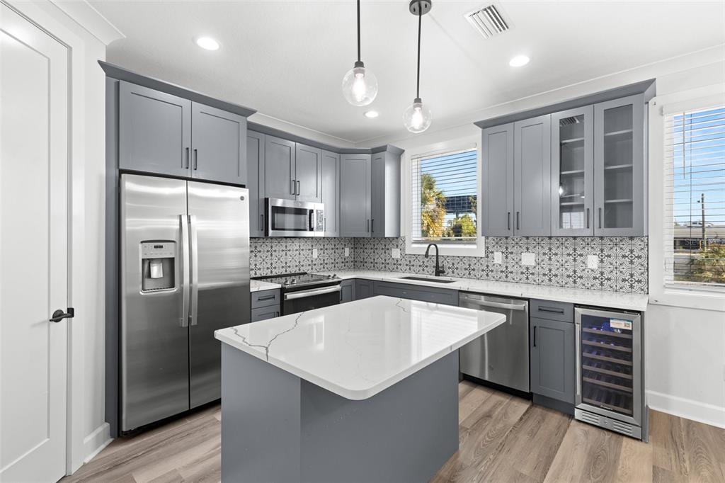 A kitchen with gray cabinets, a white quartz island, stainless appliances, and patterned tile backsplash — 1501 N MORGAN STREET UNIT 5, TAMPA, FL