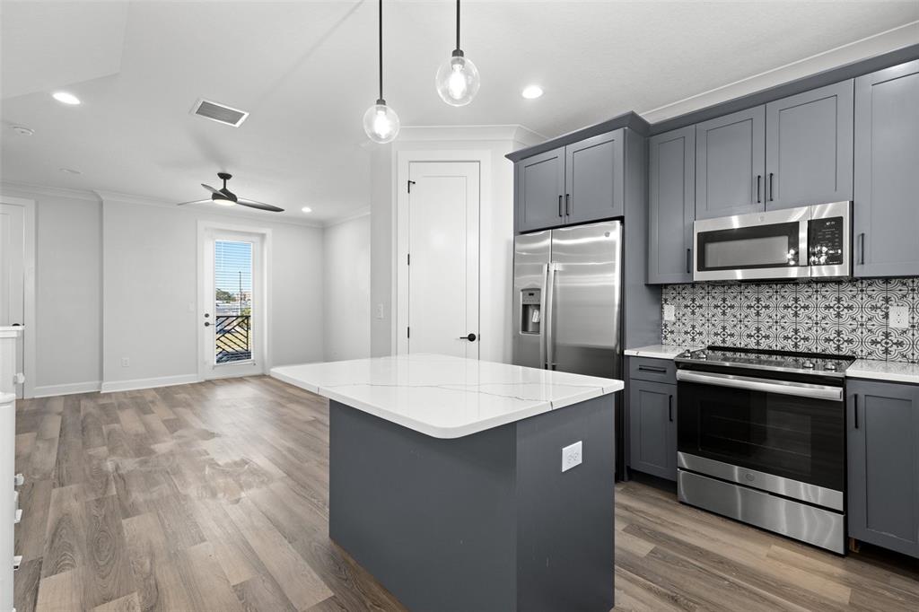 A modern kitchen features dark gray cabinets, a white quartz island, and light wood flooring — 1501 N MORGAN STREET UNIT 5, TAMPA, FL