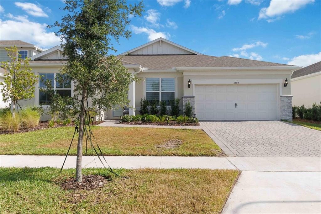 A single-story suburban house features a two-car garage, stone accents, and a paved driveway — 5503 BANYAN BAY ROAD, ST CLOUD, FL