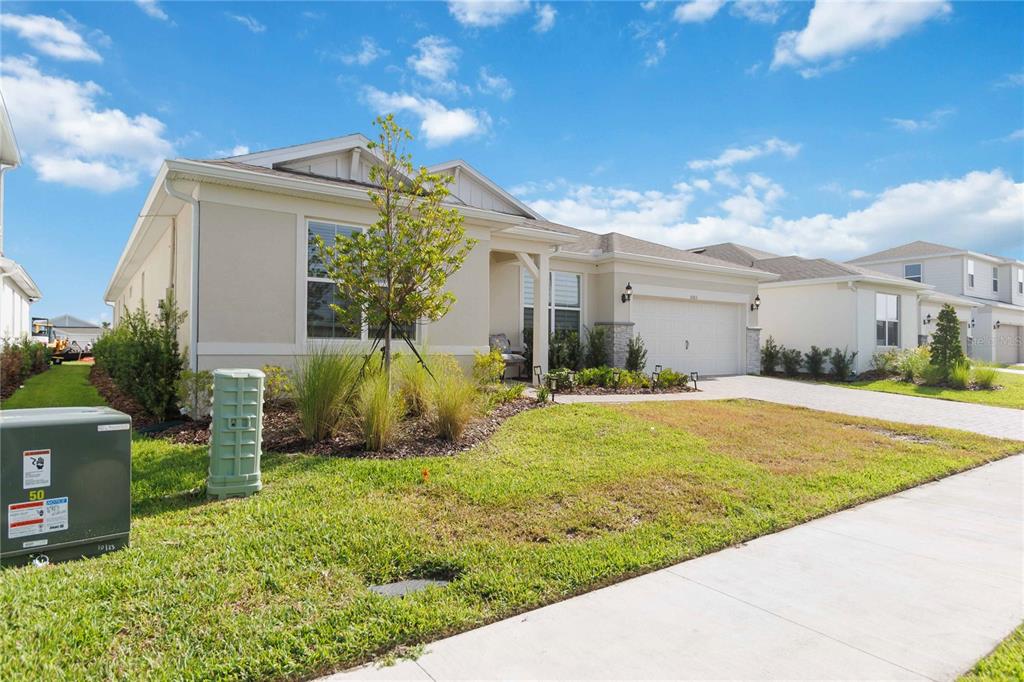 A single-story suburban house with a beige exterior, a two-car garage, and a front lawn — 5503 BANYAN BAY ROAD, ST CLOUD, FL
