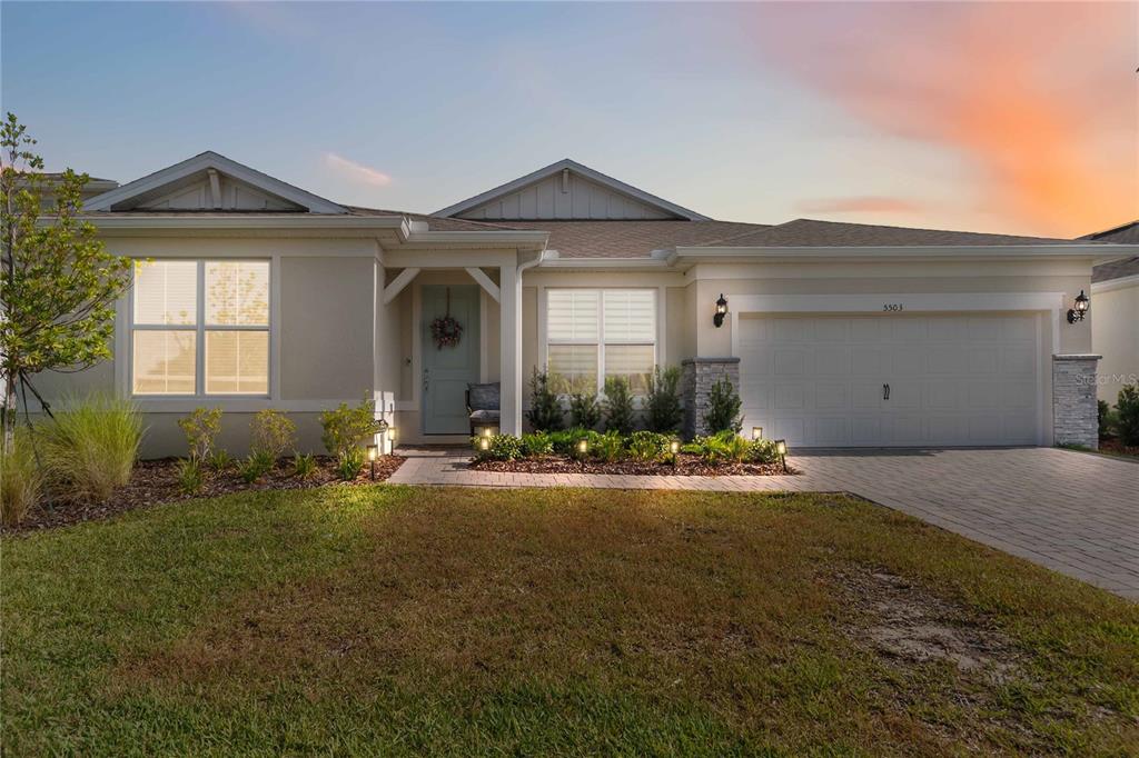 A single-story house with a light-colored exterior, a two-car garage, and a paved walkway — 5503 BANYAN BAY ROAD, ST CLOUD, FL