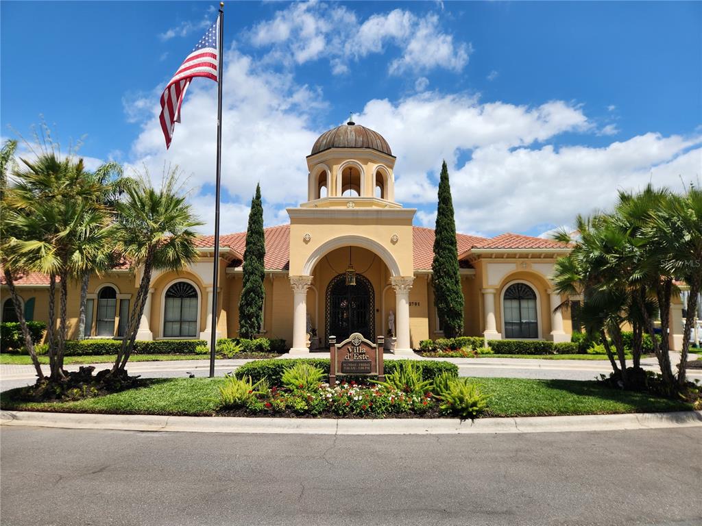 The exterior of a Mediterranean-style clubhouse features a central dome, arched entryway, and palm trees — 2733 VIA CIPRIANI UNIT 810A, CLEARWATER, FL