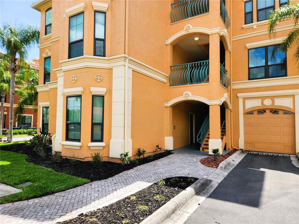 A multi-story orange stucco building with a paved walkway, a garage, and balconies — 2733 VIA CIPRIANI UNIT 810A, CLEARWATER, FL