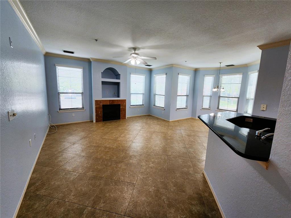 An open-concept living room features light blue walls, tile flooring, and a corner fireplace — 2733 VIA CIPRIANI UNIT 810A, CLEARWATER, FL