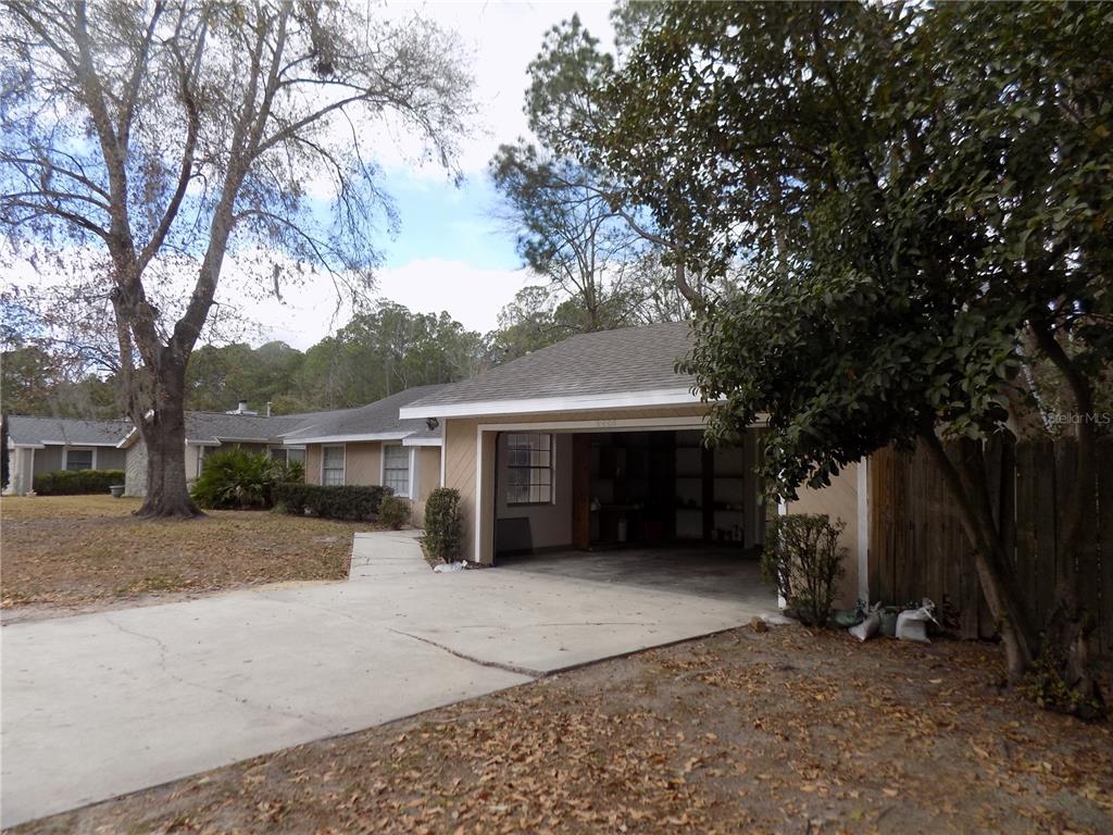 A single-story house features a concrete driveway leading to an open-air attached carport — 4408 NW 44 PLACE NW, GAINESVILLE, FL