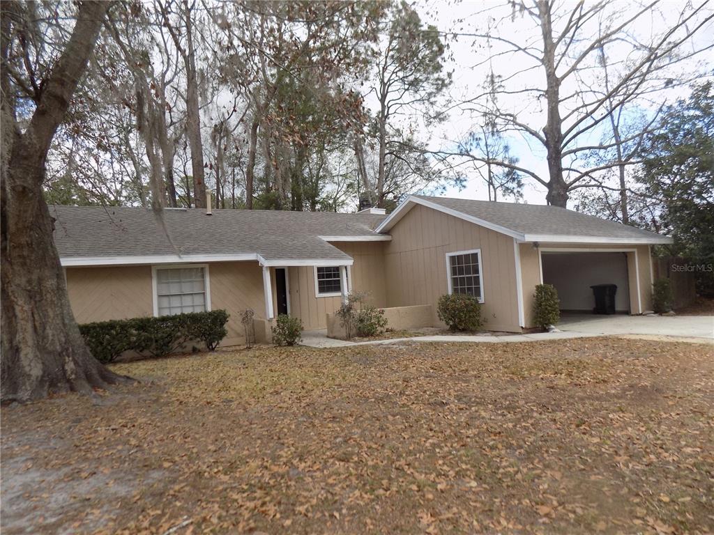 A single-story tan house with a garage and large trees in the front yard — 4408 NW 44 PLACE NW, GAINESVILLE, FL