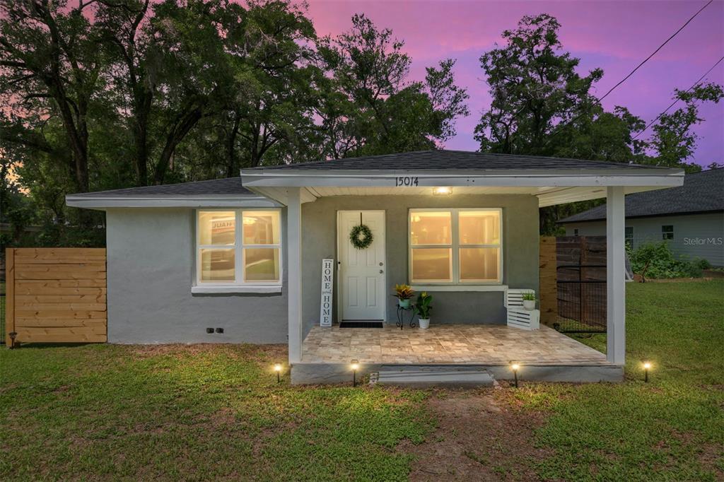 A gray house with a covered front porch, tiled floor, and a wooden fence — 15014 NW 135TH TERRACE, ALACHUA, FL