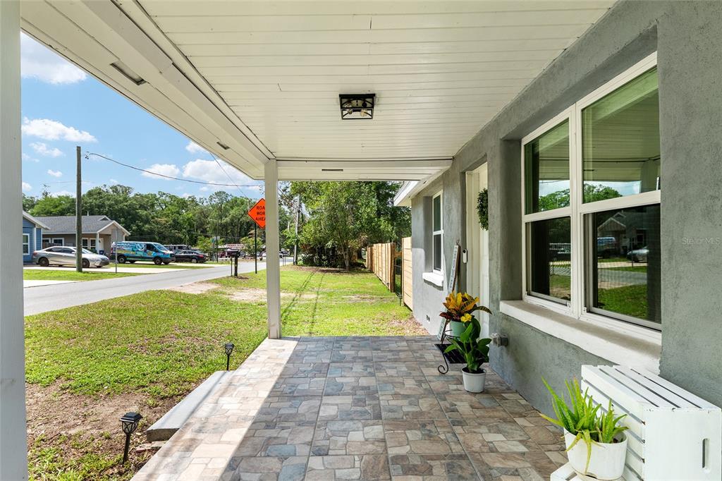 A gray single-story house features a covered front porch, a tiled floor, and wood fencing — 15014 NW 135TH TERRACE, ALACHUA, FL