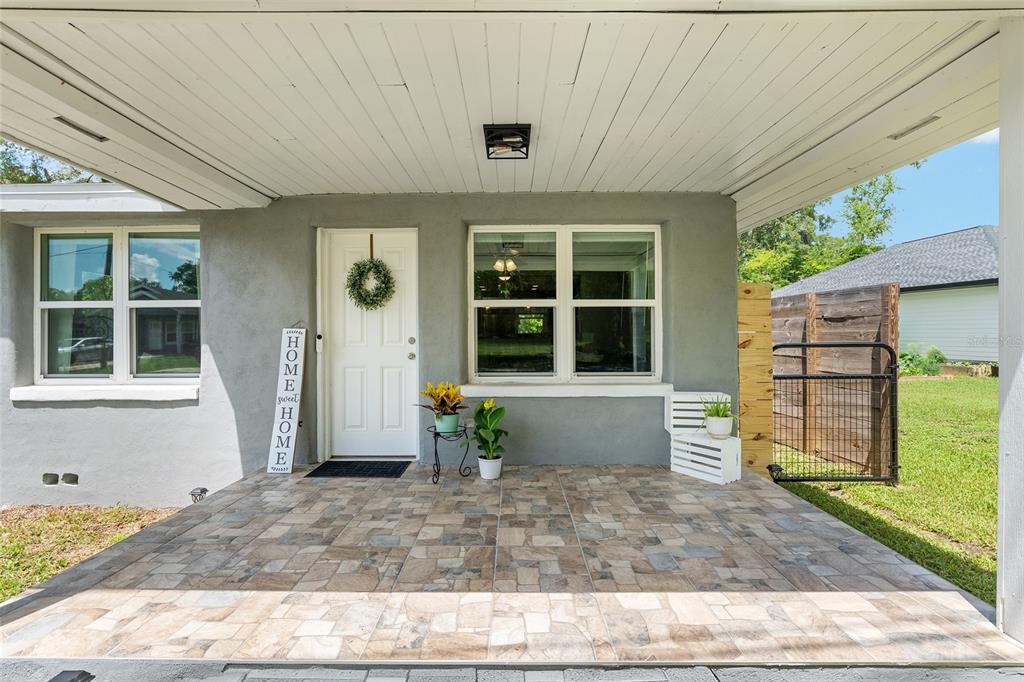 A covered porch with tiled flooring overlooks a residential street and a grassy yard — 15014 NW 135TH TERRACE, ALACHUA, FL