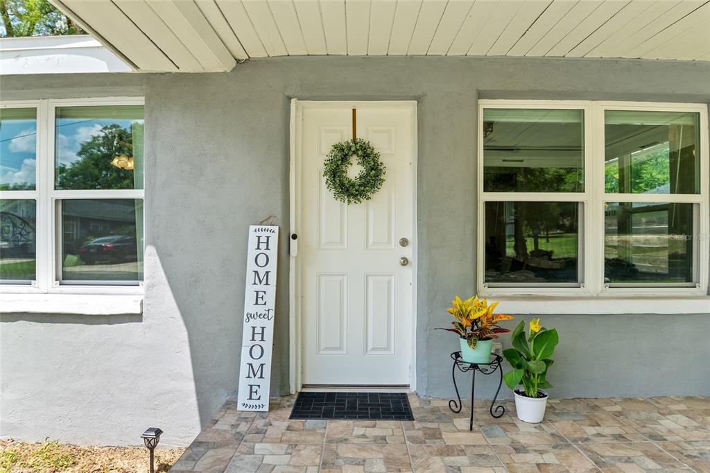 A covered front porch features tiled flooring, a white front door, and two windows — 15014 NW 135TH TERRACE, ALACHUA, FL
