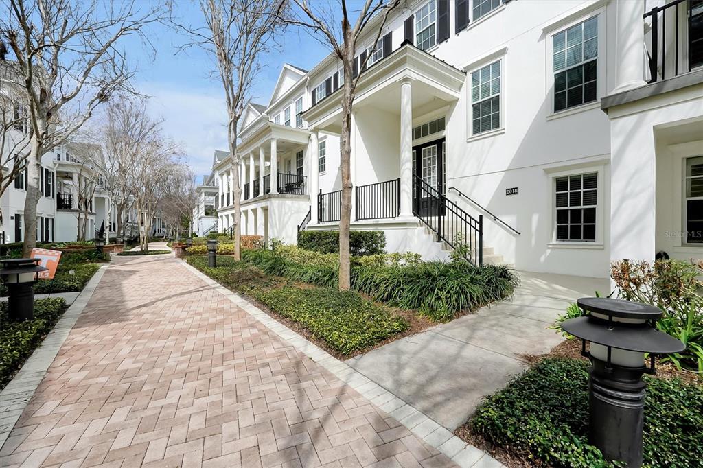 A brick walkway leads to the front entrance of a white multi-story townhouse — 2018 BRINK ALLEY, ORLANDO, FL