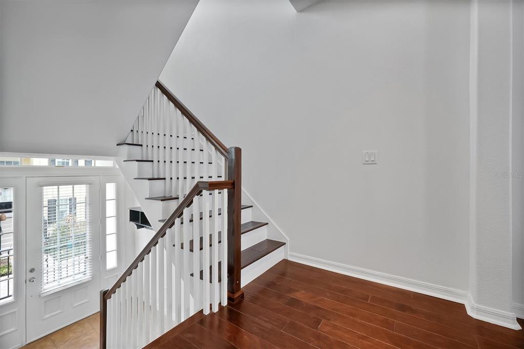 A staircase with white railings and dark wood treads leads upward in a bright foyer — 2018 BRINK ALLEY, ORLANDO, FL