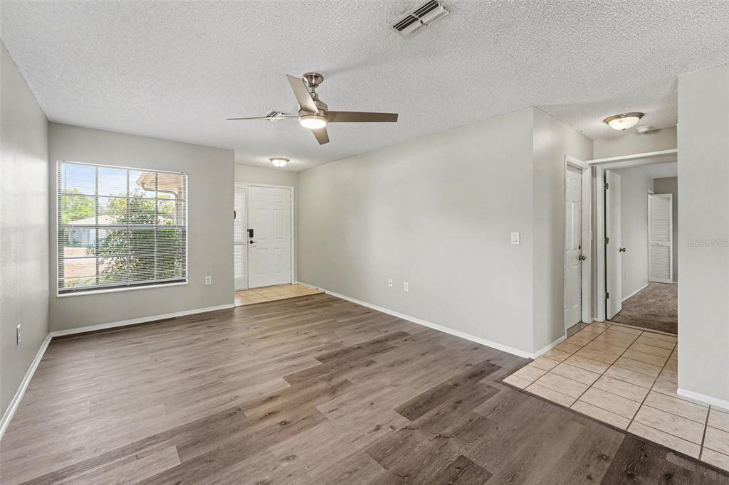 A living room with wood-look flooring, a ceiling fan, and a tiled entryway — 10161 HEATHCLIFF STREET, SPRING HILL, FL