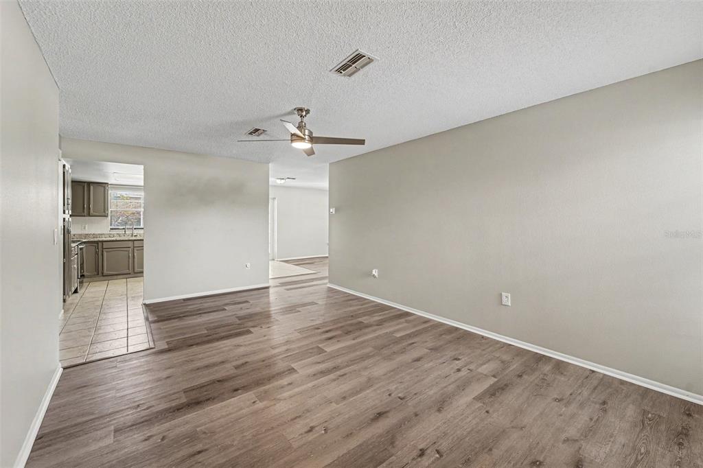 A living room with wood-look flooring, a ceiling fan, and an adjacent kitchen — 10161 HEATHCLIFF STREET, SPRING HILL, FL