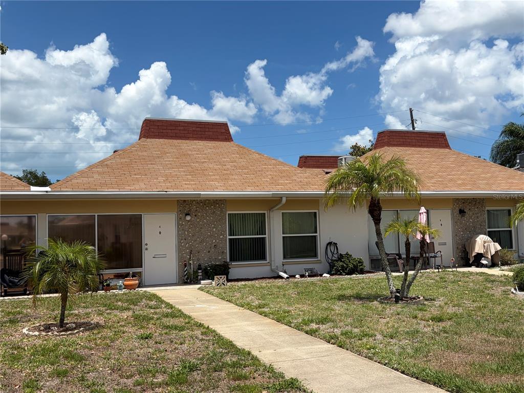 A single-story duplex with tan stucco walls, stone accents, and two prominent roof cupolas — 4345 TAHITIAN GARDENS CIRCLE UNIT C, HOLIDAY, FL