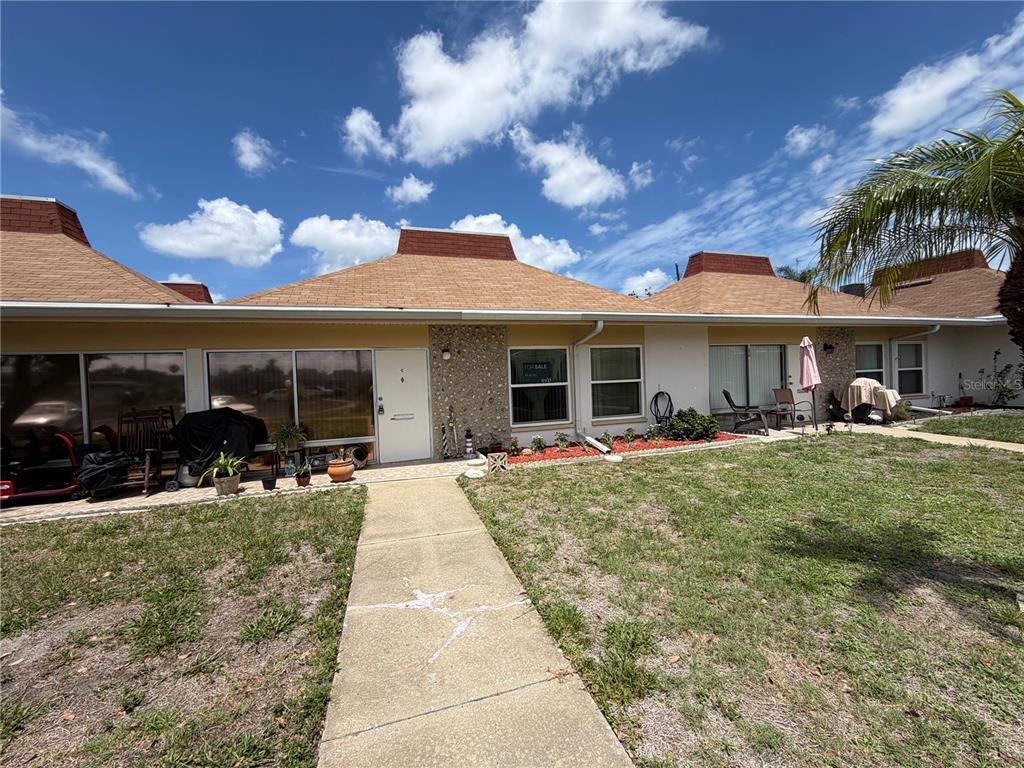 A single-story residential building with a tan exterior, stone facade, and a brown shingled roof — 4345 TAHITIAN GARDENS CIRCLE UNIT C, HOLIDAY, FL