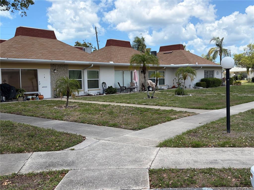 A row of single-story residential units with brown hip roofs and a shared lawn — 4345 TAHITIAN GARDENS CIRCLE UNIT C, HOLIDAY, FL