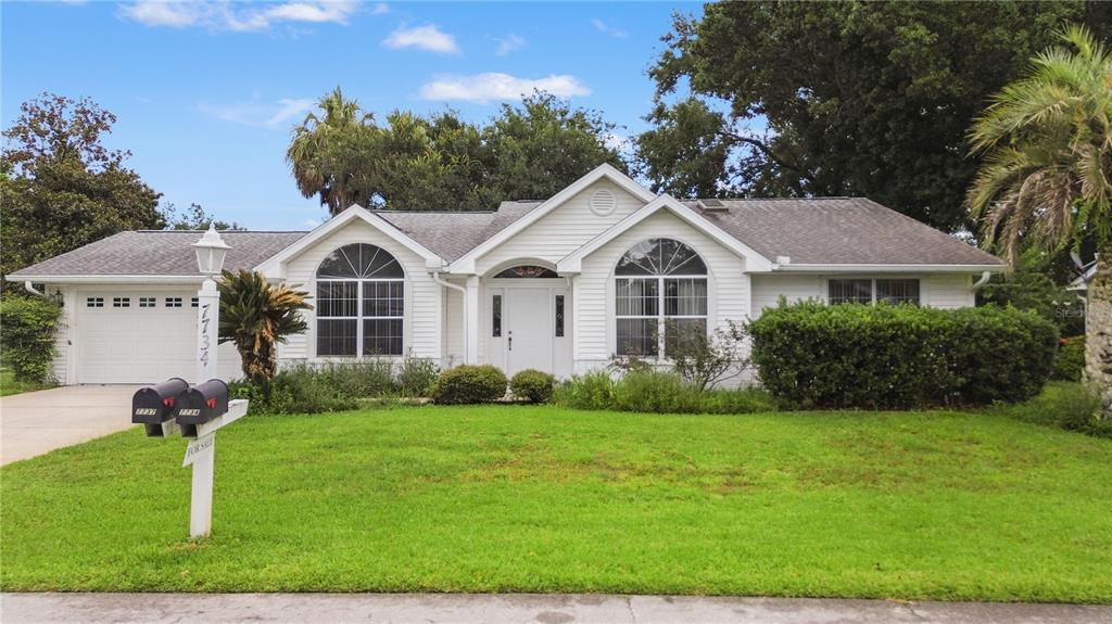 A single-story white house with a two-car garage and a large front lawn — 7734 SW 114TH LOOP, OCALA, FL