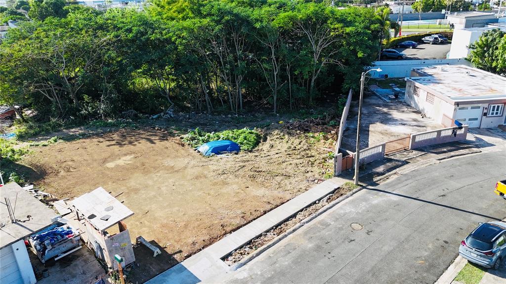 An aerial view shows a vacant, cleared residential lot next to a small building — URB. JARDINES DE LOIZA C-8, LOIZA, PR