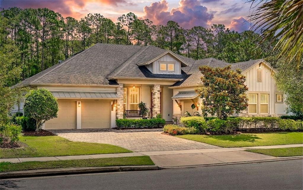 A single-story house with a stone-accented facade, two-car garage, and a paved driveway at sunset — 13137 LOWER HARDEN AVENUE, ORLANDO, FL