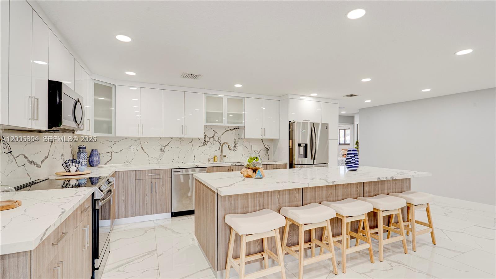 A modern kitchen features white upper cabinets, wood-tone lower cabinets, and a marble-topped island — 34 Atlantic Drive, Marathon FL 33037, MARATHON, FL