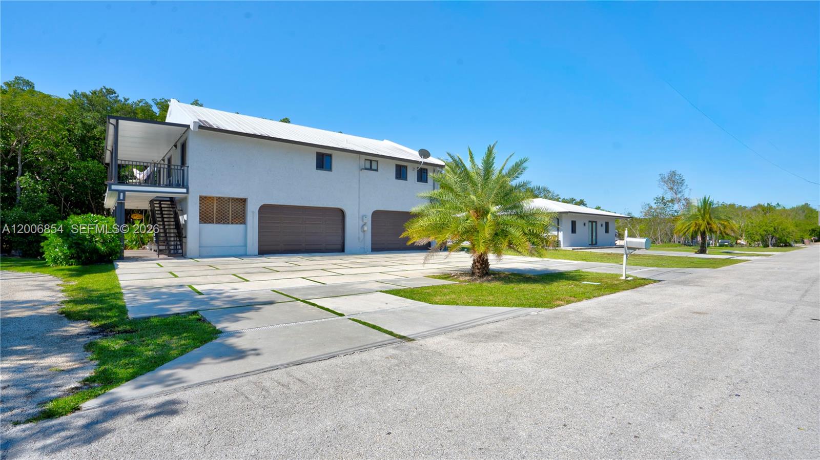 A two-story house with a white exterior, two garage doors, and a paved driveway — 34 Atlantic Drive, Marathon FL 33037, MARATHON, FL