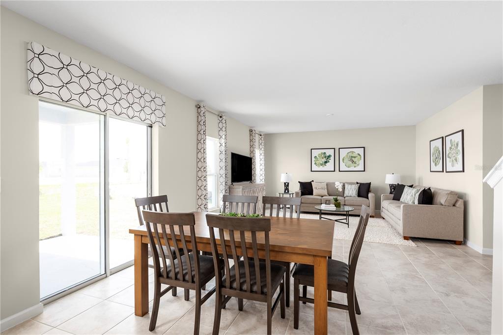 A dining area with a wooden table and chairs opens into a living room with sofas — 6939 SUNDIAL DRIVE, LAKELAND, FL