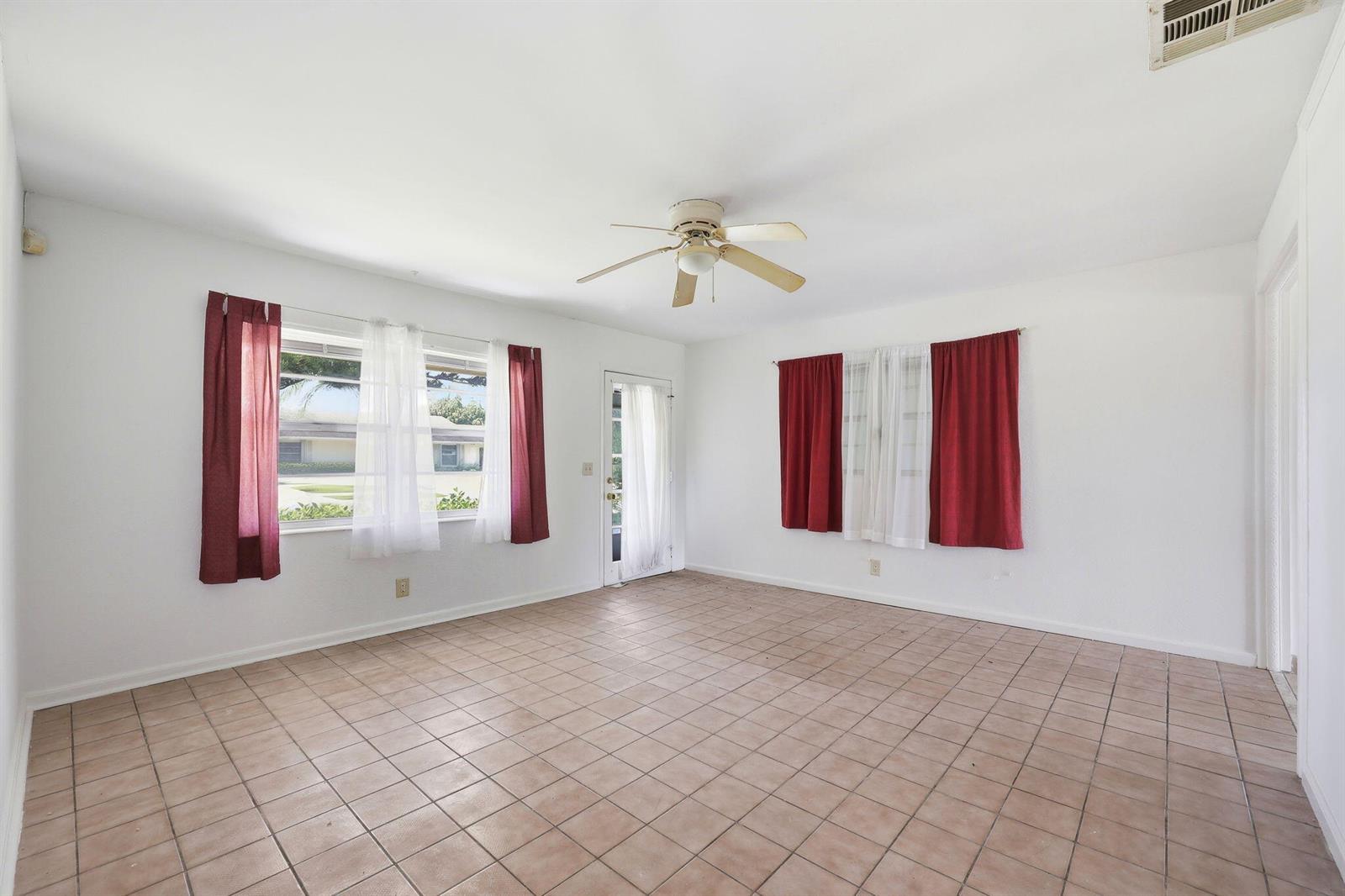 An empty room with white walls, tile flooring, a ceiling fan, and red window curtains — 115 SE 11th Avenue, Boynton Beach FL 33435, BOYNTON BEACH, FL