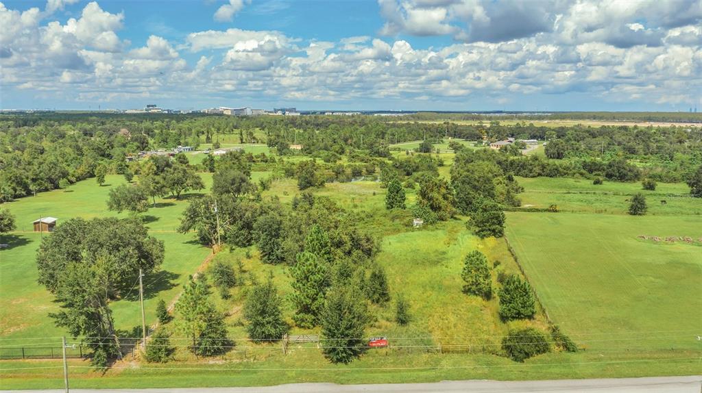 An aerial view shows a grassy, partially wooded vacant lot bordered by a road — 4281 TIMBER LANE, KISSIMMEE, FL