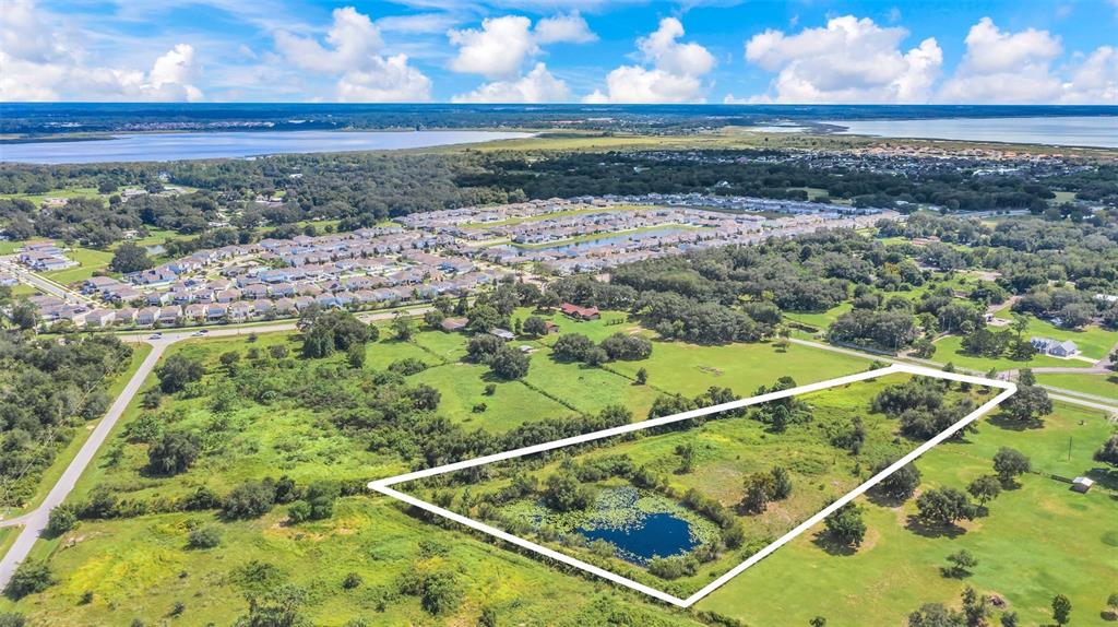 An aerial view shows a grassy lot with a small pond outlined in white — 4281 TIMBER LANE, KISSIMMEE, FL