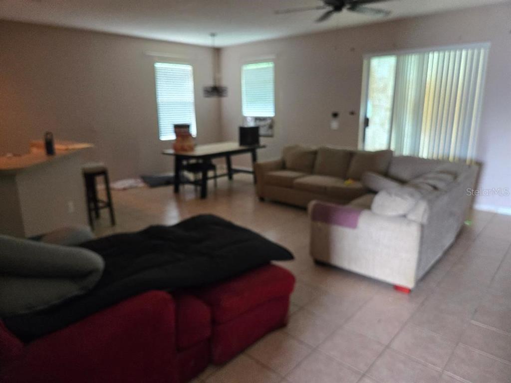 A living room with tile flooring, a large sectional sofa, and an adjacent dining area — 2633 WALDEN WOODS DRIVE, PLANT CITY, FL