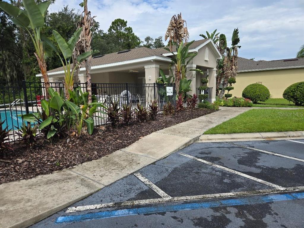 An outdoor pool area with a covered patio, black metal fencing, and tropical landscaping — 2633 WALDEN WOODS DRIVE, PLANT CITY, FL