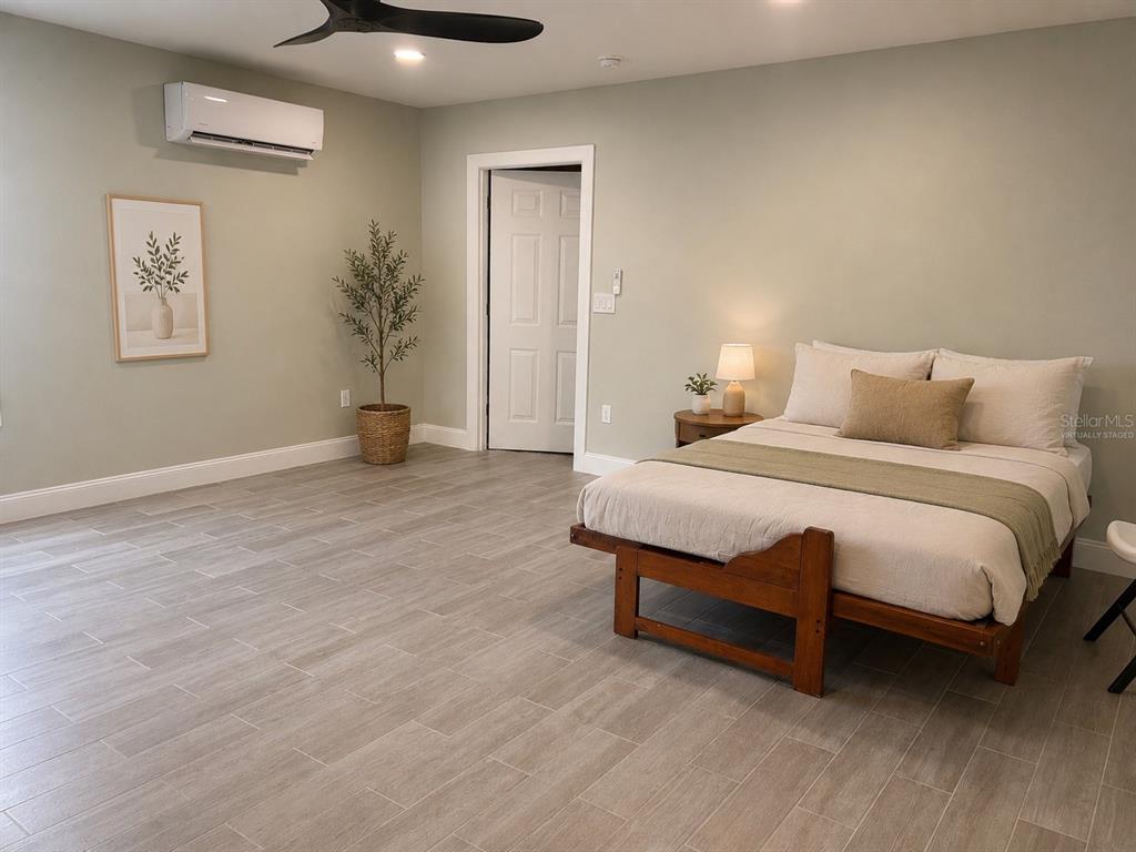 A bedroom features light-colored tile flooring, a wooden bed frame, and a wall-mounted air conditioner — 6750 BOUGANVILLEA CRESCENT DRIVE, ORLANDO, FL
