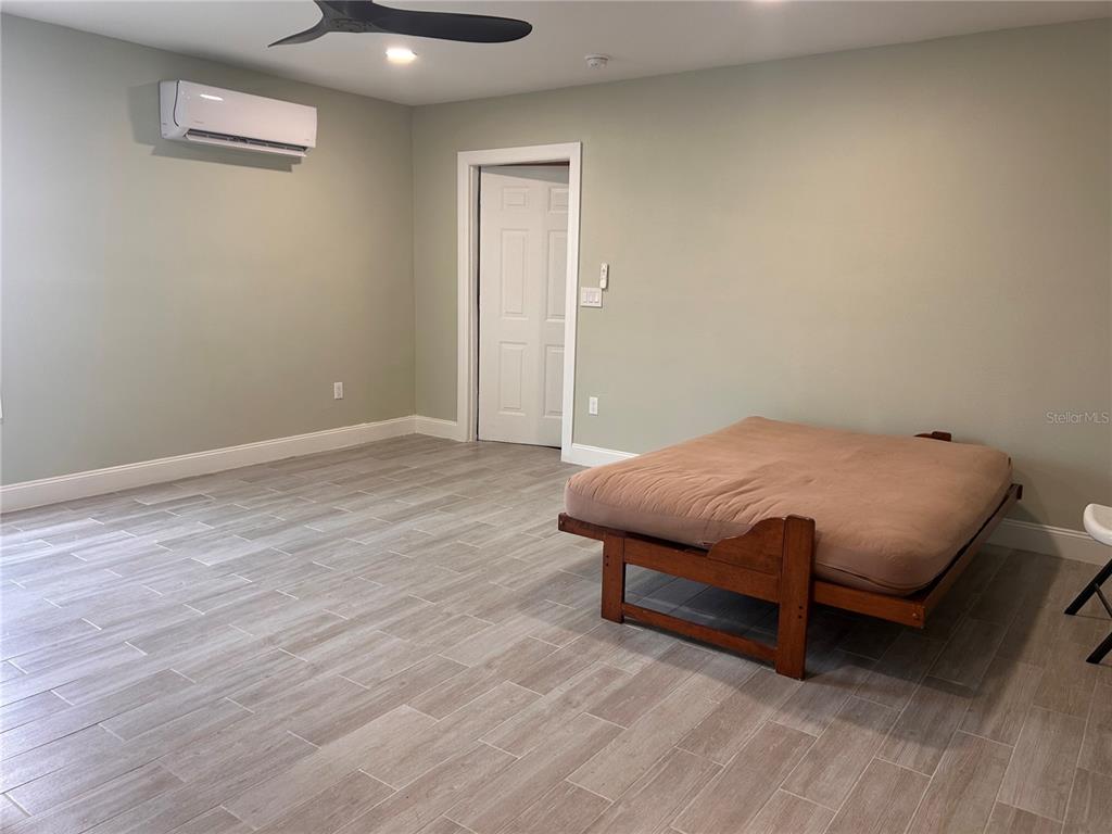 A room with light-colored tile flooring, a futon, and a wall-mounted air conditioning unit — 6750 BOUGANVILLEA CRESCENT DRIVE, ORLANDO, FL