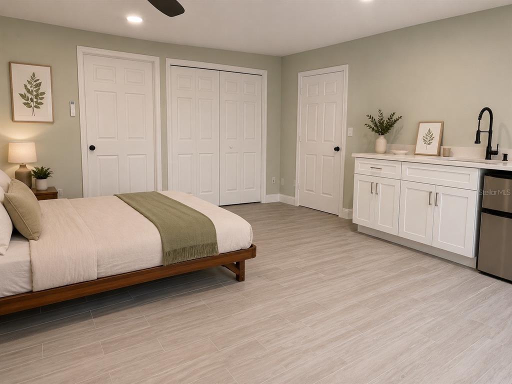 A bedroom with light green walls, wood-look tile flooring, a kitchenette, and white doors — 6750 BOUGANVILLEA CRESCENT DRIVE, ORLANDO, FL