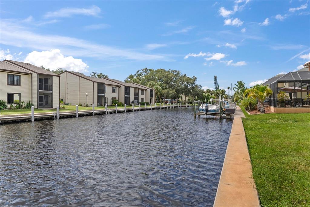 A canal view showing apartment buildings, a boat dock, and a grassy lawn — 316 MANATEE LANE, TARPON SPRINGS, FL