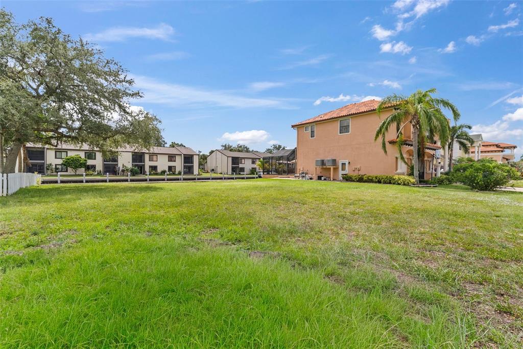 A large, grassy vacant lot sits in front of a multi-story house and apartment buildings — 316 MANATEE LANE, TARPON SPRINGS, FL