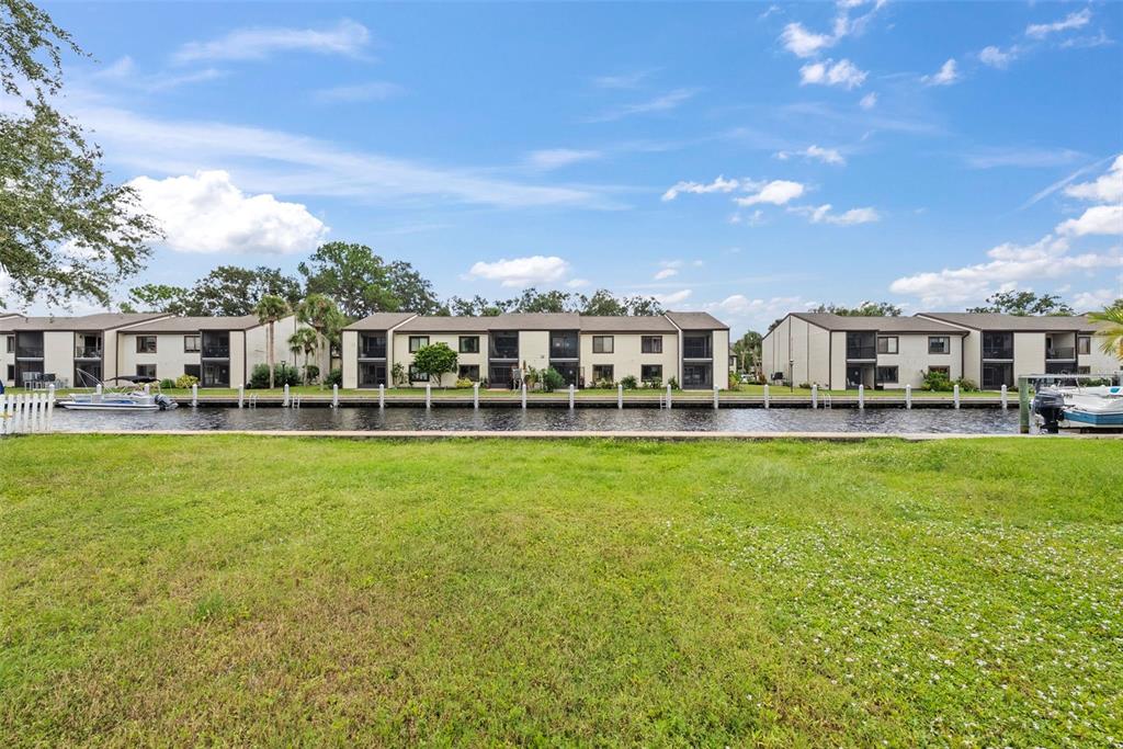 A grassy lawn overlooks a canal with boat slips and multi-story apartment buildings — 316 MANATEE LANE, TARPON SPRINGS, FL