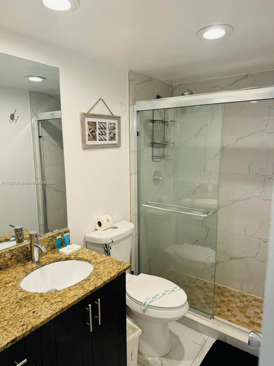 This bathroom features a granite vanity, dark wood cabinetry, and a glass-enclosed walk-in shower — 3901 S Ocean Dr # 10G, Hollywood FL 33019, HOLLYWOOD, FL