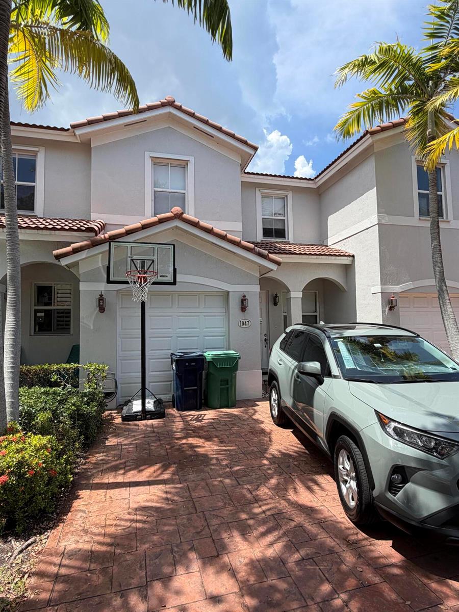 A two-story townhouse with a paved driveway, a basketball hoop, and a parked SUV — 1047 NE 208th Street, Miami FL 33179, MIAMI, FL