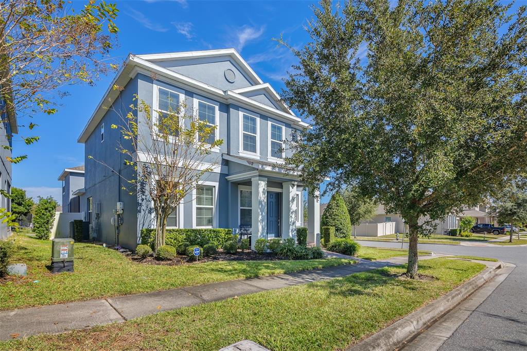 A two-story blue house with a front porch and a grassy yard under a blue sky — 15807 SWEET LEMON WAY, WINTER GARDEN, FL