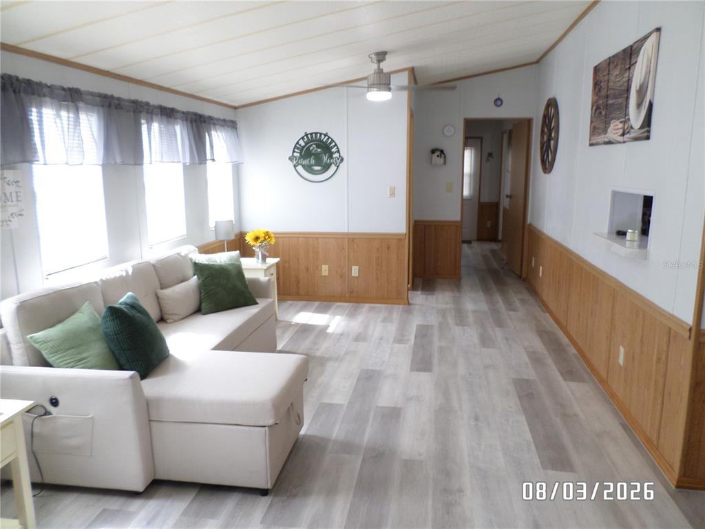 A living room features light wood-look flooring, wood wainscoting, a sectional sofa, and a ceiling fan — 83 ROAN ROAD, LAKE WALES, FL